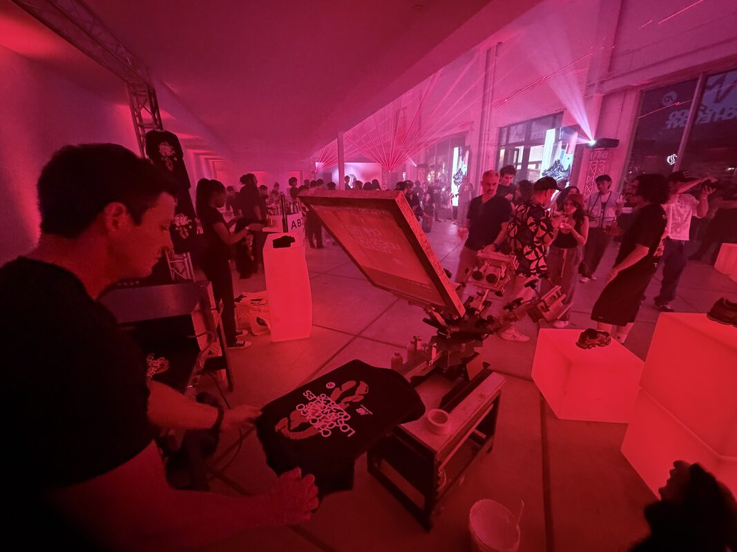 Merch Troop operator running a heat press at an on-site DTF station